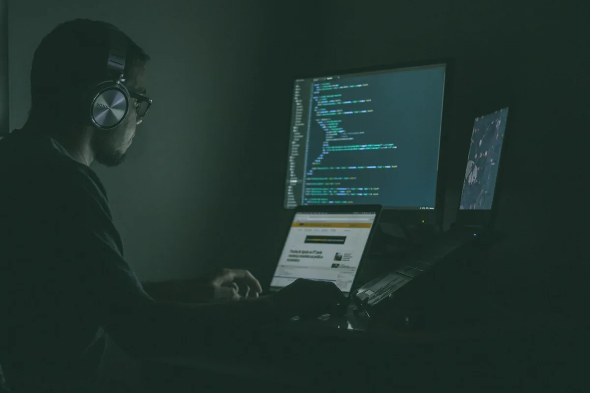 Especialista monitoreando sistemas y código en múltiples pantallas